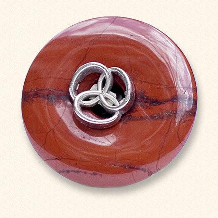 Ein Trauerknopf aus Jaspis mit einem Knopf eines geliebten Menschen darauf. Der rote Jaspis ist oft geädert.